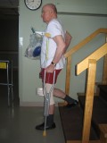 Image of a man demonstrating how to go down the stairs with one crutch and using a railing