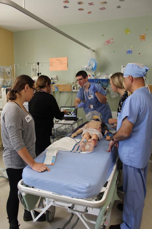 Faculty members gather around and inspect a practice dummy