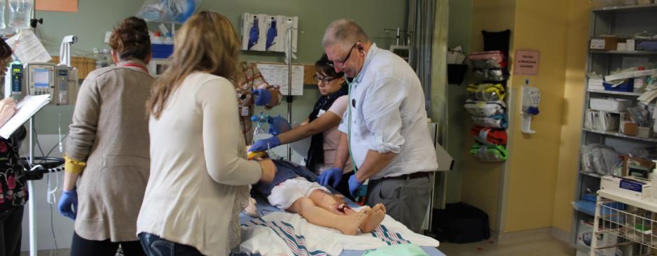 A group of faculty members is working to practice a procedure surrounding a practice dummy