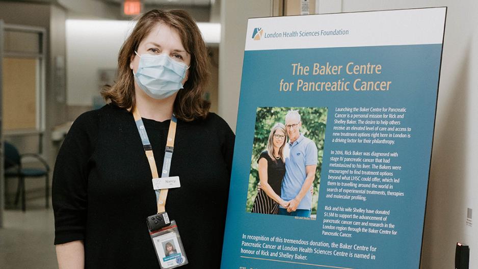 Image: Nancy Gregg, Patient Health Facilitator, The Baker Centre next to The Baker Centre signage