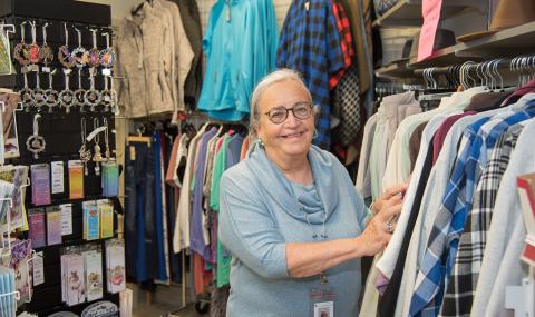 Lyn Harrison, president of the London Health Sciences Centre Auxiliary, stands in the Tower Shoppe at Victoria Hospital. She's surrounded by products from the gift shop and is touching clothing on display.