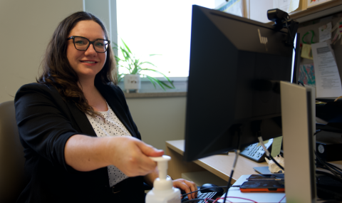 staff member smiles at camera while using alcohol based hand rub