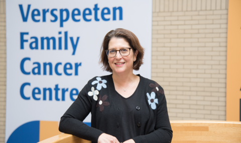 Dr. Joy Mangel stands in front of a Verspeeten Family Cancer Centre banner