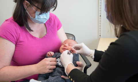 A clinician treats an infant being held by a parent. 