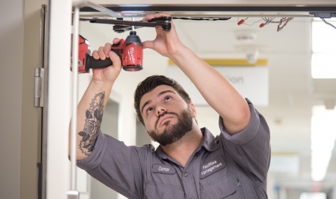 Facilities team member uses a screwdriver on a door frame