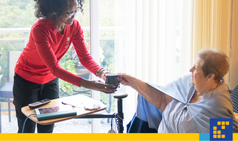 A young Personal Support Worker hands a patient a cup of tea.