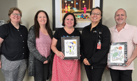A group of people posing with Indigenous artwork