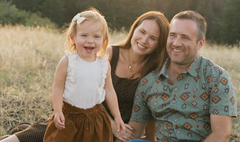 Jessica Tracey and family sitting together on grass.
