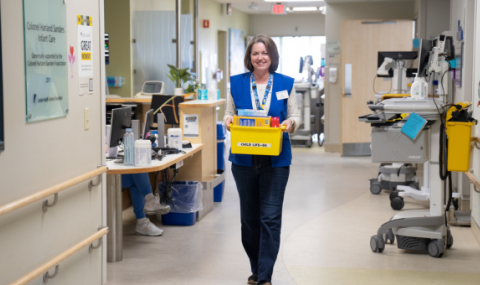 Carroll walks down the hallway on the Paediatric Inpatient Unit carrying a bin of toys.