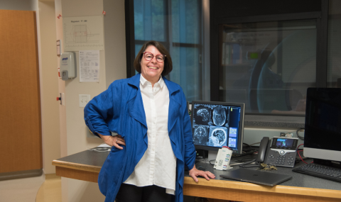 Dr. Ruth Lanuis, Scientist at LHSCRI and Psychiatrist at London Health Sciences Centre standing in front of a computer displaying a brain scan.