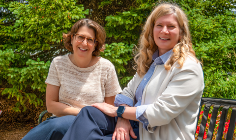 Two women sitting on a garden bench smiling