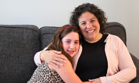Stella in a leopard print shirt hugging her mom, Sari, wearing a black shirt and pink sweater