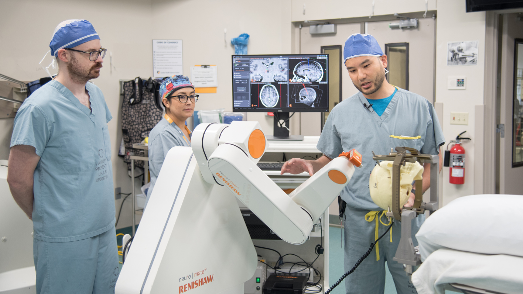 Neurosurgeon Dr. Johnathan Lau (R), Neurophysiologist Dr. Greydon Gilmore and Dr. Sonia Mejia, an epilepsy fellow from Mexico City with robot used to assist in first deep brain stimulation surgery to treat epilepsy in Canada.