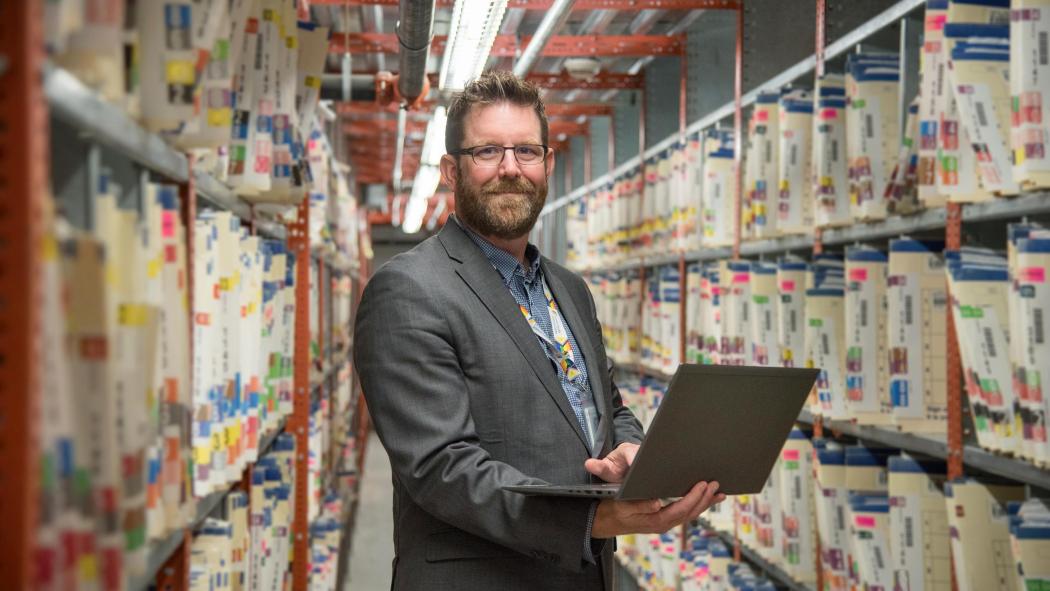 Andrew Mes, digital health executive and corporate information officer, with some of the paper files that will be fully digitized in a major LHSC project.