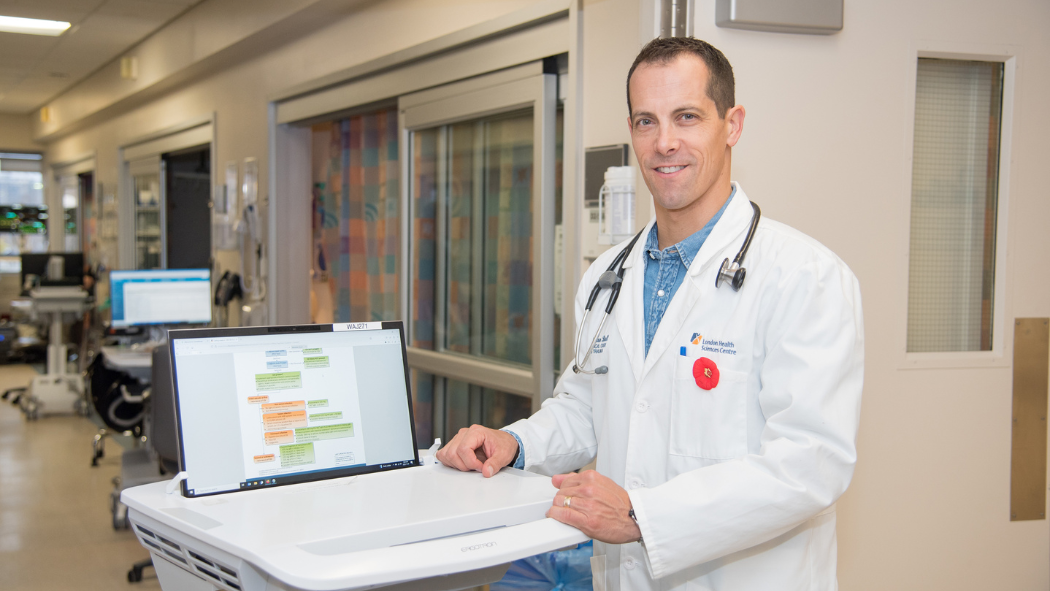 Dr. Ian Ball stands beside computer displaying digital clinical pathways and guidelines