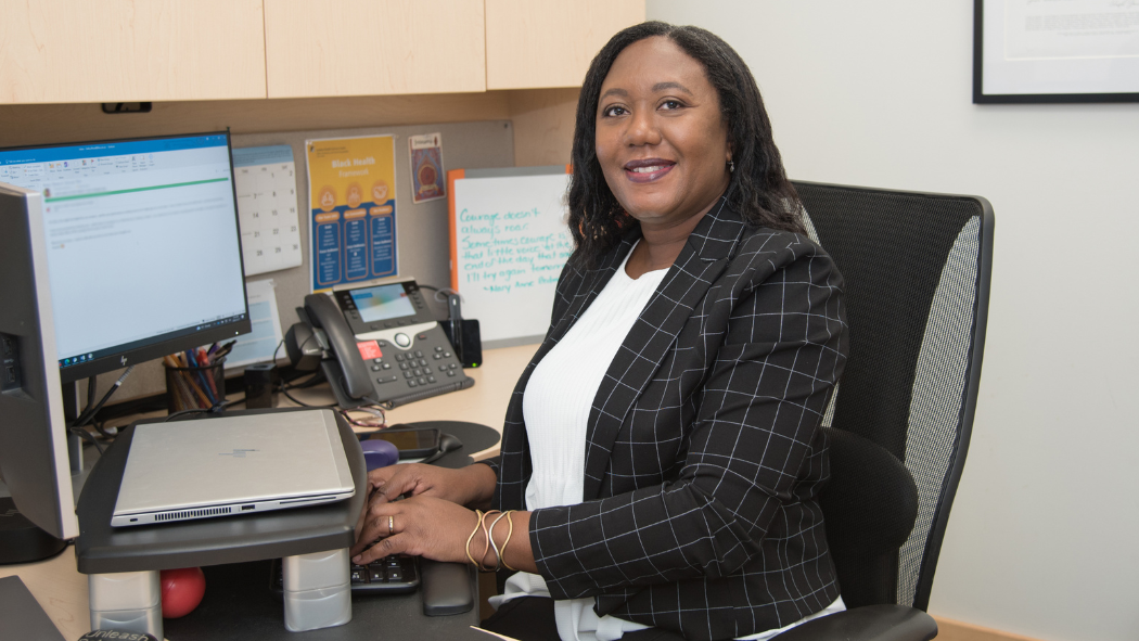 A photo of Cathy Wood, Senior Director of Black Health, sitting at a desk with a computer