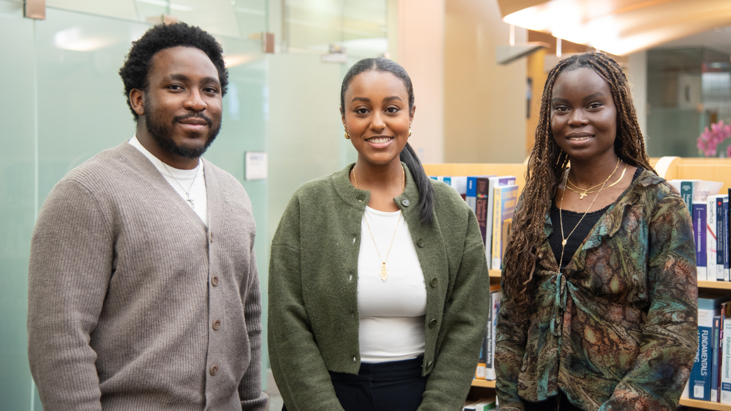 A photo of Forbehn Fossungu, Gabriella Game, and Nyechuor Deng in a library.
