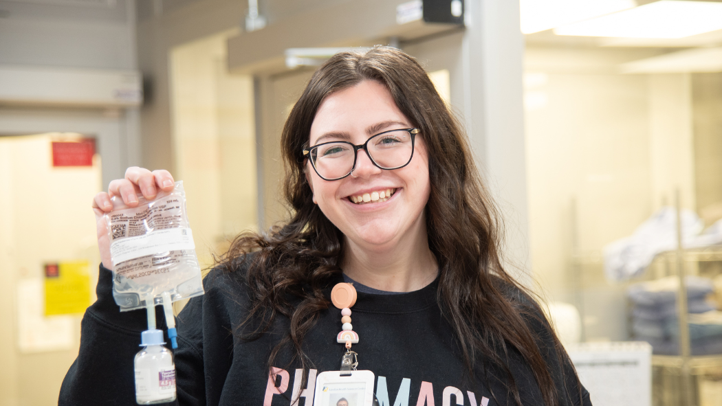 Pharmacy technician holding up a prepared antibiotic IV bag