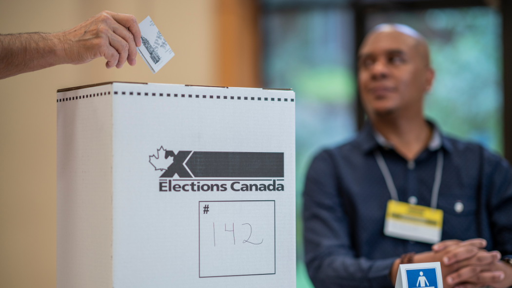 A person places their vote in an Elections Canada box.