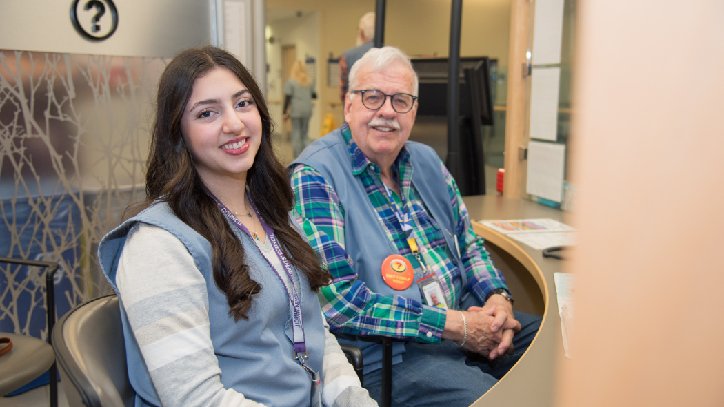 Jenna and Don sit at the Information Booth in Victoria Hospital’s B1 lobby.