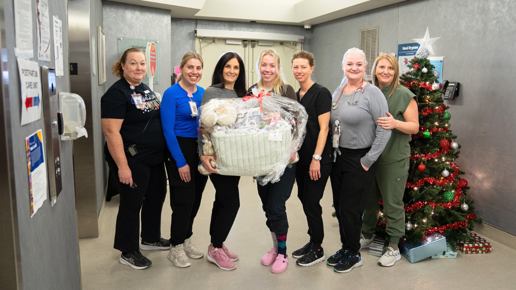 Nurses in the Post-Partum Care Unit stand holding a basket of baby supplies.