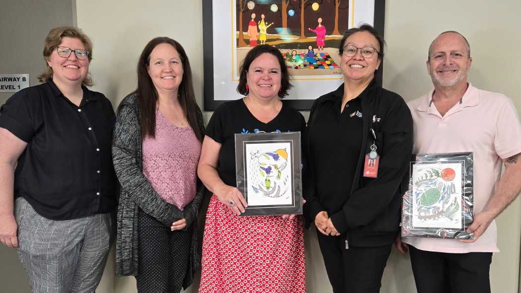 A group of people posing with Indigenous artwork