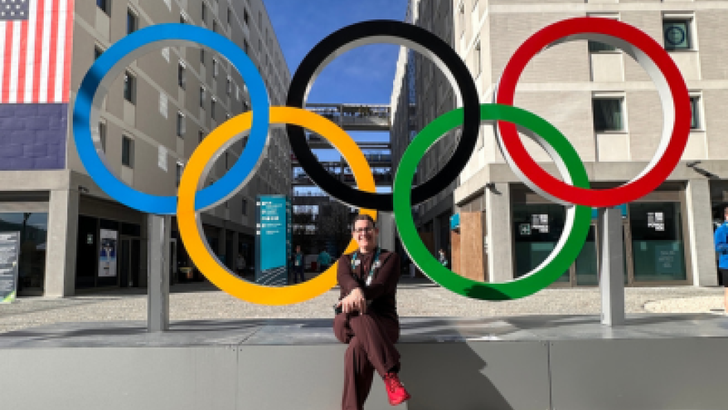Dr. Tatiana Jevremovic sits in front of the Olympic rings at the Milan Olympic village. 