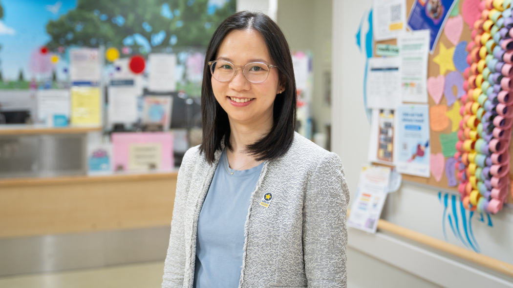 A female physician stands in a colourful hospital hallway.